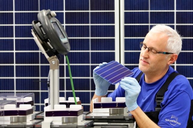 Solarworld zieht Teile der Produktion aus Freiberg ab - Ein Solarworld-Mitarbeiter der Modulfertigung prüft eine Solarzelle. Die Zellen werden in den Solarmodulen verbaut. Künftig soll die Produktion der Zellen in Arnstadt konzentriert werden.
