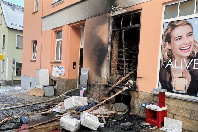 Sperrmüll in Brand geraten: Mieter in Auerbach mit Drehleiter gerettet - Der abgelöschte Sperrmüllhaufen, dahinter das Schaufenster der Parfümerie Aurel an der Schulstraße. Durch die Hitze zersprang das Glas, das Feuer drang in die Parfümerie vor. 