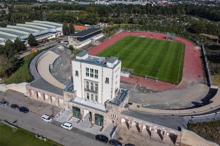 Sportforum Chemnitz: Sanierter Marathonturm übergeben – aber im Stadion herrscht Stillstand - Der Turm und die angrenzenden Gebäude wurden saniert. Ein Großteil des Stadions bleibt aber vorerst wie er ist: Die Haupttribüne bröckelt vor sich hin. Auf den Traversen wachsen Bäume.