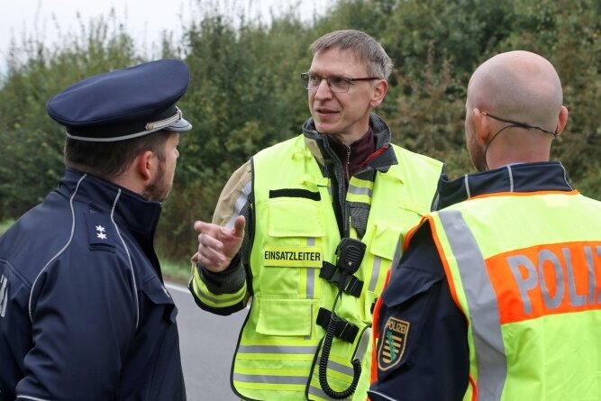 Sprengstoff-Transporter verunglückt - Einsatzleiter Dirk Werner (Mitte) von der Freiwilligen Feuerwehr Gersdorf stimmt mit den Polizisten die Maßnahmen nach der Bergung ab.