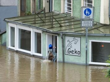 Starke Überschwemmungen nach neuen Regenfällen - Sisyphusarbeit in Passau: Mit einem Eimer wird Wasser aus einem von der Donau überfluteten Geschäft geschöpft. In der Stadt herrscht Katastrophenalarm.