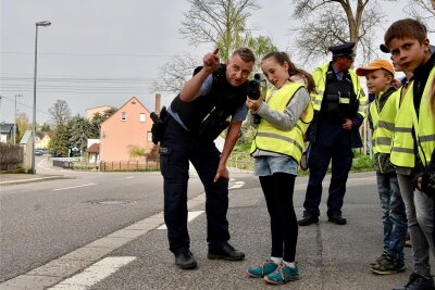 Start der Aktion „Blitz for Kids“ in Chemnitz: Trotz 30er-Zone sind viele Autos zu schnell - Polizist Rico Müller zeigt den Kindern, wie man mit dem Geschwindigkeitsmessgerät das Tempo der Autofahrer kontrolliert.