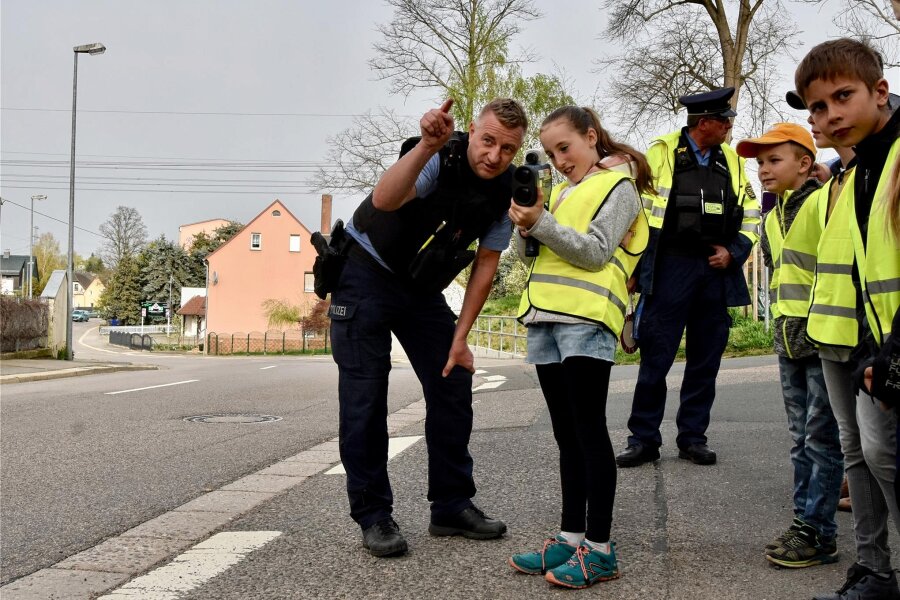 Start der Aktion „Blitz for Kids“ in Chemnitz: Trotz 30er-Zone sind viele Autos zu schnell - Polizist Rico Müller zeigt den Kindern, wie man mit dem Geschwindigkeitsmessgerät das Tempo der Autofahrer kontrolliert.