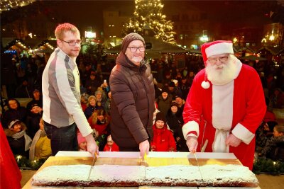 Start für den Auerbacher Weihnachtsmarkt: Der Stollen ist angeschnitten - Bäcker Robert Hartmann zerteilt mit OB Jens Scharff und dem Weihnachtsmann den 1,60 Meter langen Stollen.