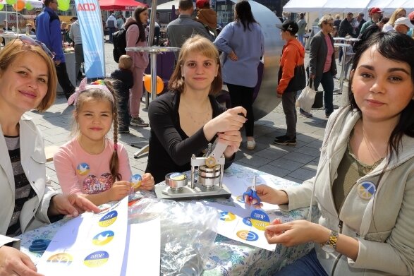 Auf dem Auer Altmarkt wurden am Sonntag auch Anstecker für den Frieden gebastelt. Die kleine Nastja und ihre Mama Ludmilla (l.) sind froh, in Sicherheit zu sein. Jenny Lederer und Lisa-Marie Lorbeer (r.) haben geholfen.