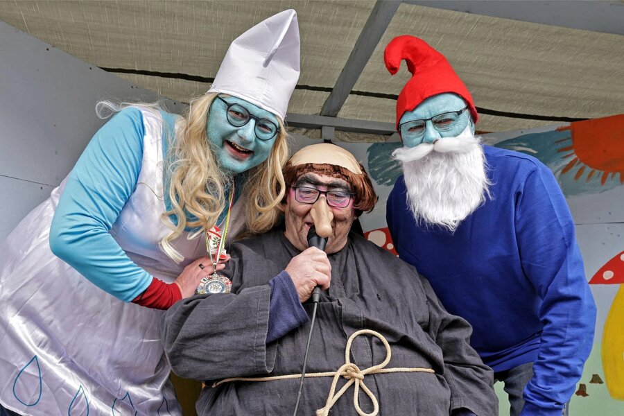 Straßenfasching in Langenchursdorf: Ein Dorf macht blau - Bürgermeister Daniel Röthig hat als Schlumpfine keine Berührungsängste zu Gargamel (Moderator Frank Haupt). Faschingsvereinschef Jürgen Morgner als Papa Schlumpf passt schließlich auf (von links).