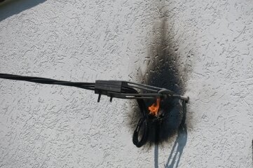 Stromkabel an Haus gerät in Brand - Die brennende Elektroleitung an der Hauswand. 