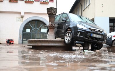Süddeutschland ächzt unter dem Hochwasser - Auf einem Brunnen in Rudersberg hängt ein durch das Hochwasser weggespültes Auto.