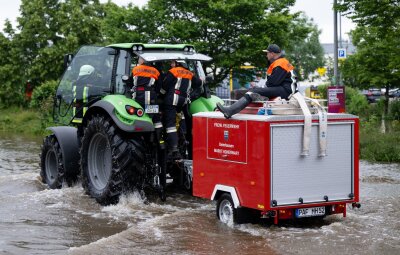 Süddeutschland ächzt unter dem Hochwasser - Feuerwehrleute fahren in Reichertshofen über eine überflutete Straße.