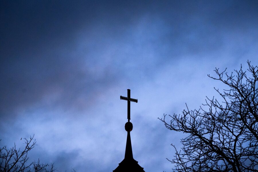 Synode zu Missbrauch und Zukunft in Minderheit - Dunkle Wolken ziehen über das Kreuz auf einer Kirche hinweg.