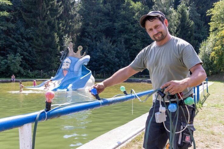 Vorbereitungen für die große Jubiläumsfeier am Wochenende: Tino Müller vom Bauhof der Gemeinde Tannenberg hängt die 80 Meter lange Lichterkette entlang der beiden Wasserbecken auf. 