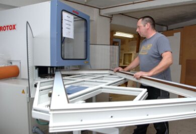 Olaf Meinelt, Vorarbeiter der Tischlerei Hainich im Bereich Kunststoff-Fensterbau, beim Bestücken eines CNC-Verputzautomaten für Kunststoffprofile. 