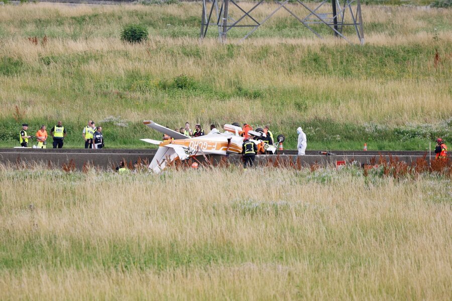 Tote bei Absturz von Sportflugzeug auf Autobahn bei Paris - Polizisten und Rettungskräfte stehen an der Absturzstelle der Cessna bei Collégien.