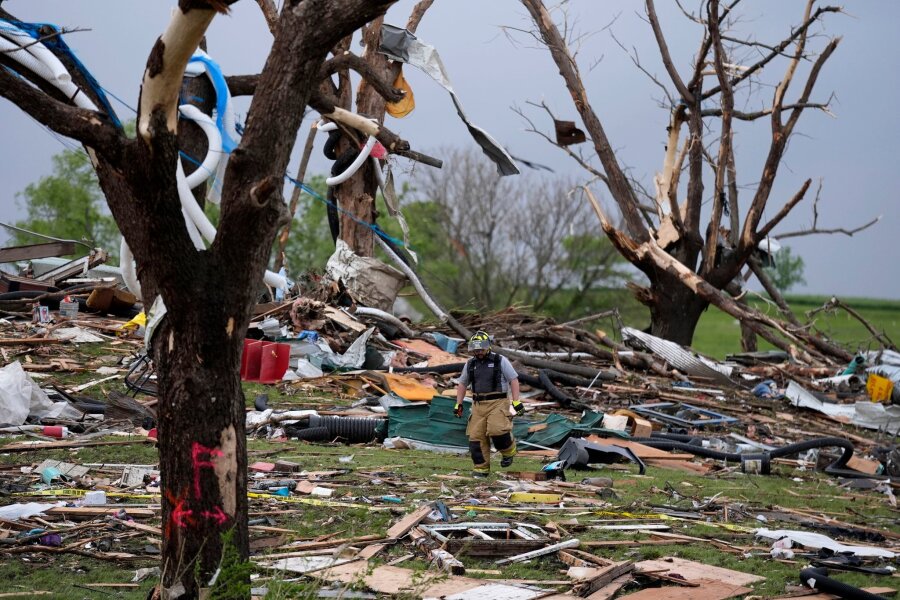 Tote und Schäden nach Tornados in den USA - Ein Feuerwehrmann geht in Greenfield, Iowa, durch die Trümmer von Häusern, die vo einem Tornado zerstört wurden.