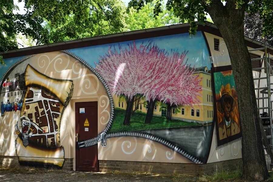 Trafohäuschen am Glauchauer Johannisplatz trägt jetzt Kunst-Graffiti statt Schmierereien - Die Wand des Trafohäuschens zur Johannisstraße hin zeigt Kirschbäume vor einem Haus am Johannisplatz und die sogenannte Wissenstankstelle mit Stadtplanteil.