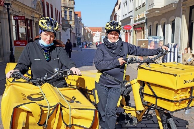 Verena Bungarten (r.) und Katja Bischoff touren mit ihren Post-Elektrorädern durch die Gassen der Freiberger Altstadt, hier auf der Burgstraße.