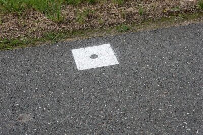 Triebel: Rätselhafte Markierungen beschäftigen Ämter - Weiße Quadrate mit einem Loch in der Mitte sind auf Straßen in den Gemeinden Triebel und Eichigt zu sehen.