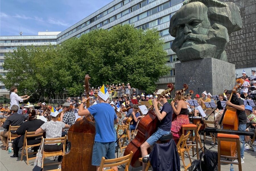 Fast 200 Musiker aus verschiedenen Ländern haben sich für gemeinsame Proben am Karl-Marx-Monument in Chemnitz zusammengefunden. Wegen der Hitze haben sich viele von ihnen mit Sonnenhüten aus Papier ausgestattet.