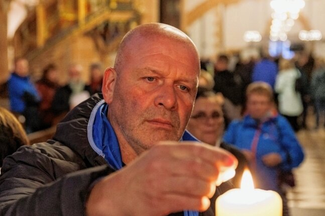 Trotziges Signal nach Berlin: Das Licht bleibt an im Erzgebirge - Unternehmer Torsten Köhler zündete nach der Friedensandacht in Sankt Annen eine Kerze an.