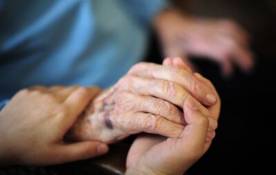 Über 260.000 Menschen in Sachsen von Angehörigen gepflegt - Eine Pflegekraft hält in einem Seniorenheim die Hand einer Bewohnerin.