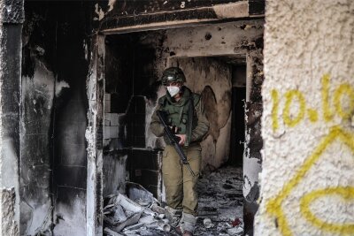 Überleben oder Sterben in Israel: Glauchauer im Wechselbad der Gefühle - Ein israelischer Soldat inspiziert ein verwüstetes Haus in Kfar Aza. In dem Dorf wohnt Poly Amikam, eine langjährige Freundin der Glauchauer Annekathrin und Bodo Siegle.