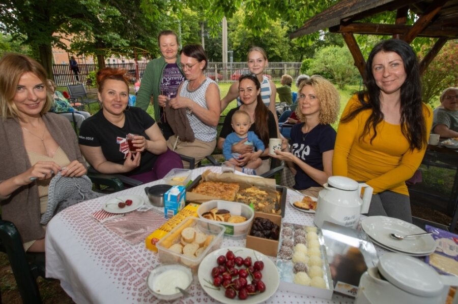 Olga Kotov (Mitte, mit Strickarbeit) übersetzt mit Tochter Sophie (hinten) für die Ukrainerinnen im Paulushaus.Bei einem Strick-Picknick kamen die Frauen im Garten bei Kuchen und Piroschki zusammen. 