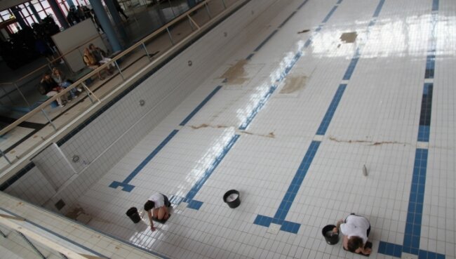 Kunstaktion im Schwimmbad: Mit Zahnbürste und Lappen reinigen auf diesem Bild Rachel Pursglove und Karolina Rupp die Bodenfliesen des leerstehenden Beckens. 