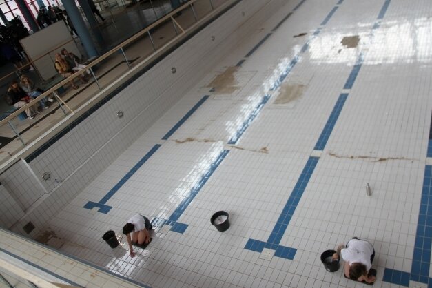 Kunstaktion im Schwimmbad: Mit Zahnbürste und Lappen reinigen auf diesem Bild Rachel Pursglove und Karolina Rupp die Bodenfliesen des leerstehenden Beckens. 