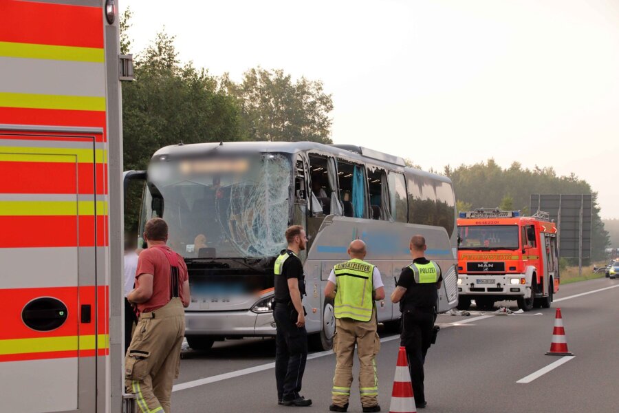 Unfall mit Reisebus auf A24 - 16 Menschen verletzt - Rettungskräfte stehen neben dem beschädigten Reisebus auf der Autobahn 24.