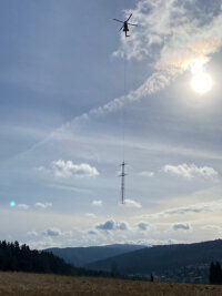 Ungewöhnlicher Anblick über Aue: Wieso fliegen hier Strommasten durch die Luft? - Eine Hubschrauberfirma aus der Schweiz hat die Masten geflogen.
