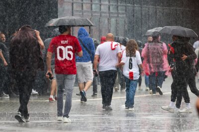 Unwetter in Teilen Deutschlands - Fanzonen betroffen - Das haben sie sich sicherlich anders vorgestellt: Fussballfans in Dortmund laufen im strömenden Regen zum Stadion.
