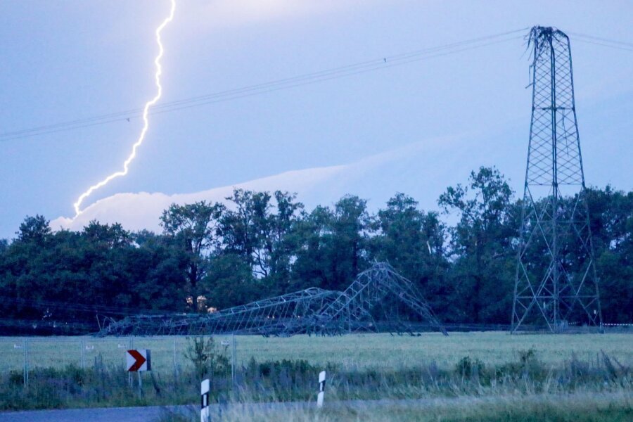 Unwetter: Schäden durch Hagel und Sturm - Ein Blitz entlädt sich hinter einem umgeknickten Strommast.