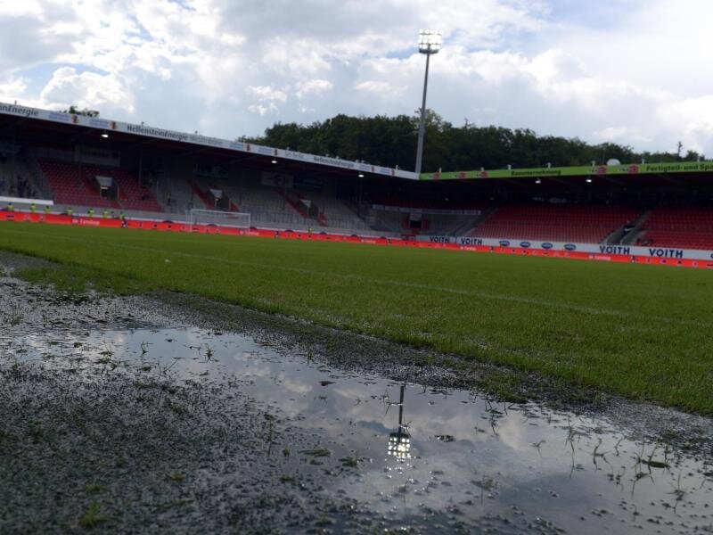 Unwetter: Spiel zwischen Heidenheim und Aue abgebrochen - Das Flutlicht spiegelt sich in einer Pfütze neben dem Spielfeld.