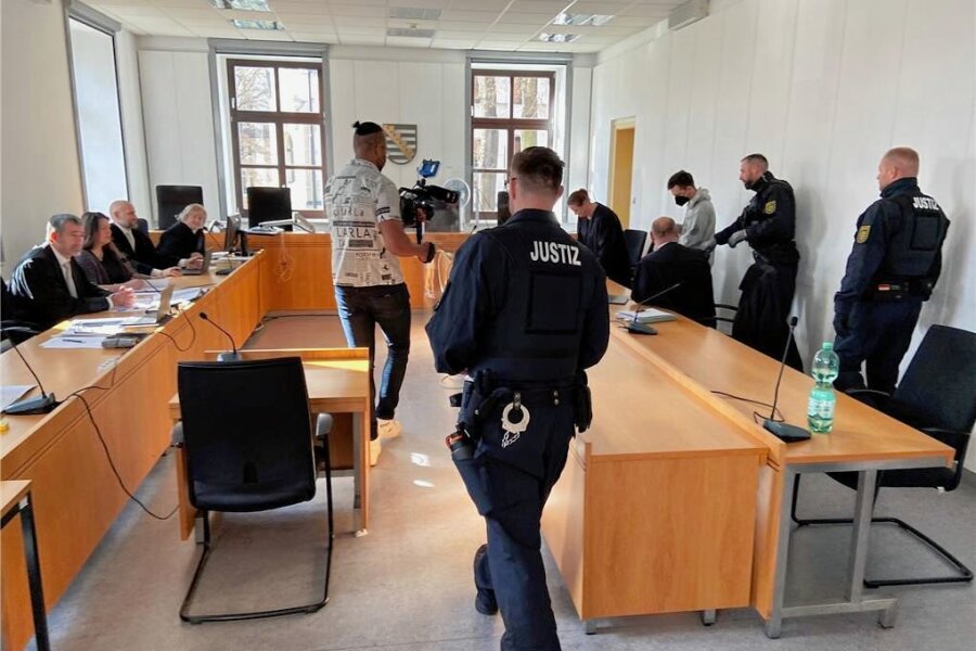 Urteil ohne bekanntes Motiv: Chemnitzer erhält wegen zweifachen Totschlags beinahe Höchststrafe - Der Angeklagte (hinten rechts) wird in Handschellen und Fußfesseln in den Gerichtssaal geführt. 