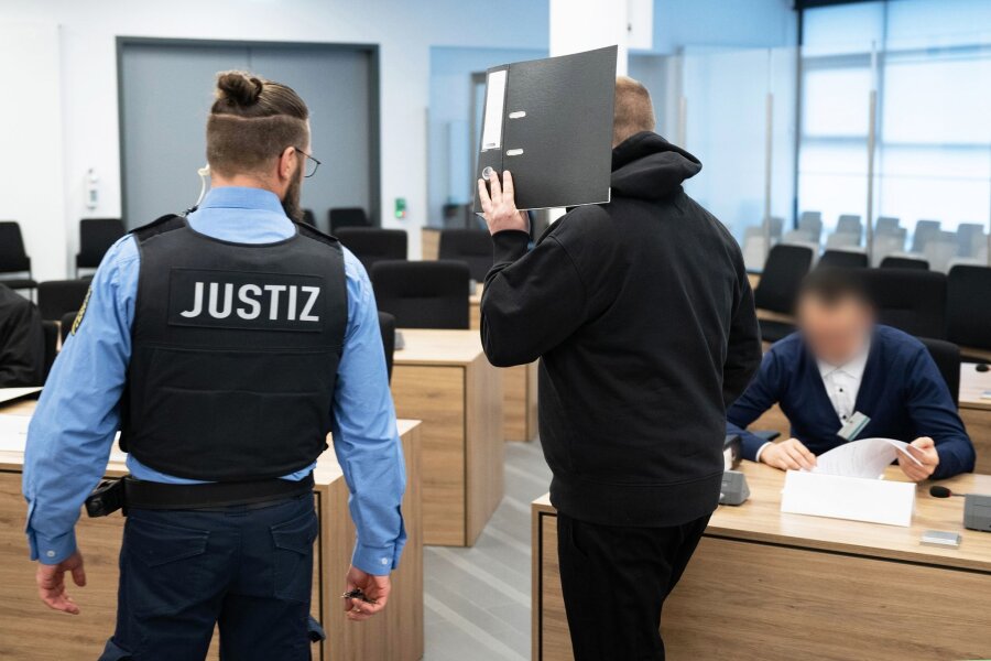 Urteile im Prozess um rechtsextremen Verlag "Der Schelm" - Haftstrafe für Leipziger Ex-NPD-Politiker - Ein Angeklagter (M) wird vor Beginn der Verhandlung in einen Saal des Oberlandesgerichts geführt.