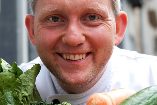 Veganer Koch: «Wir können jeden überzeugen» - Robert Beck, Koch im vegetarischen Restaurant "Hiller", sitzt im September 2012 in Hannover an einem Tisch voll Gemüse vor dem Restaurant.