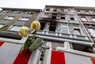 Verdächtiger für vierfachen Mord in Solingen ermittelt - Eine weiße Rose an einer Absperrbake vor dem Brandort in Solingen am 27. März.