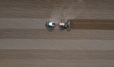 Verkaufsstopp ostdeutscher Agrarflächen besiegelt - Ein Landwirt fährt mit seinem Traktor und angehängter Drille über ein Feld und bringt Saatgut in den Boden aus. (Luftaufnahme mit einer Drohne).