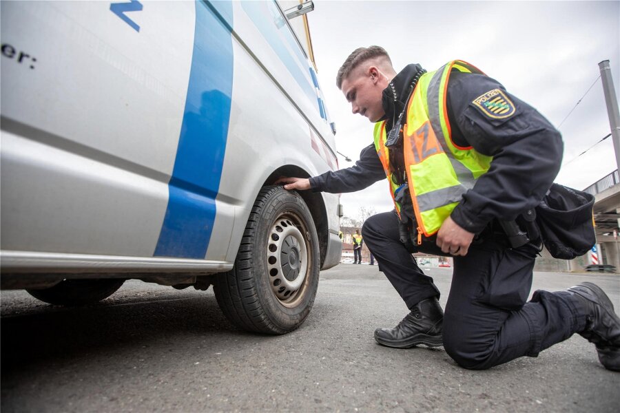 Verkehrskontrollen in Plauen: Polizei fasst mehrere gesuchte Personen - Polizeikontrolle in Plauen: Ein Beamter der Bereitschaftspolizei kontrolliert das Reifenprofil eines Autos.