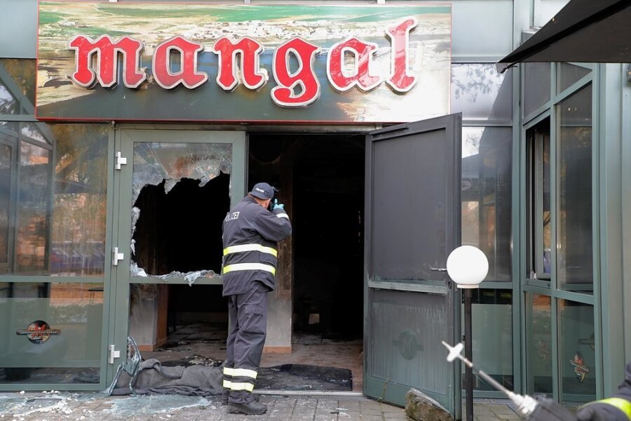 Am Morgen nach dem Feuer: Ein Beamter der Polizei dokumentiert vom Eingang des ausgebrannten Restaurants aus den Tatort.