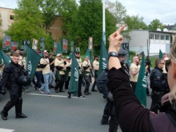 Versammlungsbehörde kann rechtsextremen Aufmarsch in Plauen nicht verlegen - Teilnehmer eines rechten Aufmarsches der Partei "Der dritte Weg" sind zu sehen. Eine Demonstrantin protestiert. 