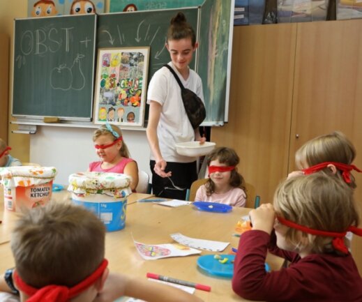 Der Freiwilligendienstleistende Antony Peger verteilt an Kinder der Grundschule in Langenberg bei einem Projekt Früchte. Mit verbundenen Augen sollen diese gekostet und so erkannt werden. 