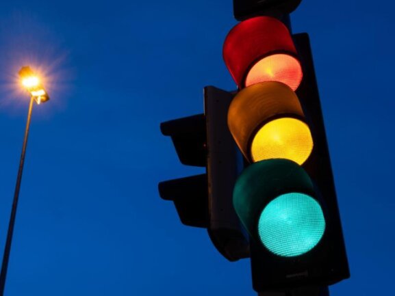            Eine Ampel zeigt am frühen Morgen die Farben rot, gelb und grün.