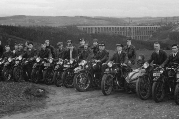 Mitglieder des Motorradklubs Triumph Mylau und Umgebung am 7. Mai 1933 vor einer Ausfahrt ins Waldhotel "Zöbischhaus" in Bad Reiboldsgrün. Die Aufnahme mit Blick auf die Göltzschtalbrücke entstand in Reinsdorf nahe des längst abgerissenen Klublokals "Zur schönen Aussicht". 