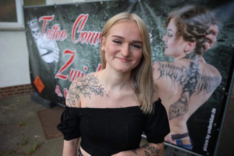 Von frivol bis maritim: Westsachsen zeigen ihre Lieblings-Tattoos - Hübsch anzusehen: Sophie Benti aus Zwickau präsentiert ihre Blumen-Tätowierung auf der rechten Schulter vor dem Plakat der Tattoo Convention Zwickau.