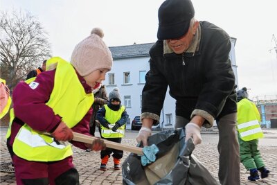 Wachsamen Blicken der Planitzer Mülldetektive entgeht nichts - Opa Claus Männel unterstützt die kleinen Mülldetektive. Er hält für Frieda Funke den Müllsack auf, in dem sie einen blauen Einweghandschuh entsorgt.