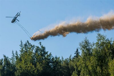 Waldgebiete zwischen Glauchau und Oelsnitz werden ab Mittwoch aus der Luft gekalkt - Ein Hubschrauber bringt Kalk über einem Waldstück aus.