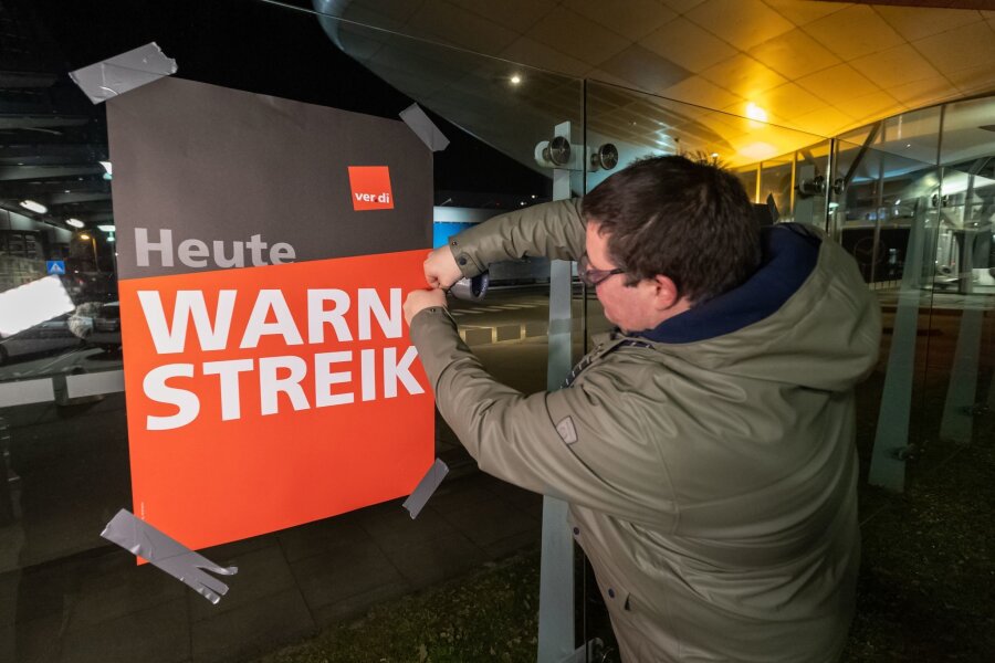 Warnstreiks treffen zahlreiche Fluggäste - Streikende hängen Plakate mit der Aufschrift "Warnstreik" bei der Lufthansa Technik auf. Mit erneuten Warnstreiks gleich mehrerer Berufsgruppen legt die Gewerkschaft Verdi am Donnerstag und Freitag wichtige Teile des deutschen Luftverkehrs lahm.