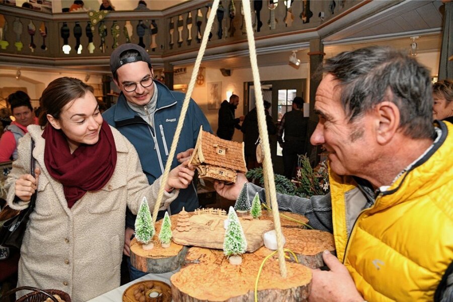 Warum der Hobbymarkt in der Kapelle Neuensalz bei den Besuchern so gut ankommt - Begeistert waren Elouise Kremling und Alexander Wolf (Mitte), die sich besonders für die Holzkunst von Thomas Günther aus Stützengrün interessierten.