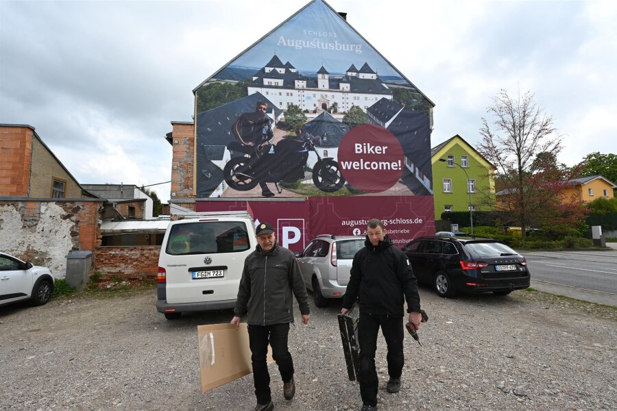 Warum ein riesiger Motorradfahrer am Jägerhof Augustusburg stoppt - Am Standort Gaststätte und Kino Augustusburg Jägerhof sind jetzt zwei Giebel verdeckt worden, um das Stadtbild zu verbessern. Uwe Schwarz (links) und Ronny Walter haben die Planen angebracht.